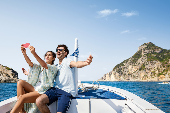 Couple taking a selfie aboard a boat along the Mediterranean coastline